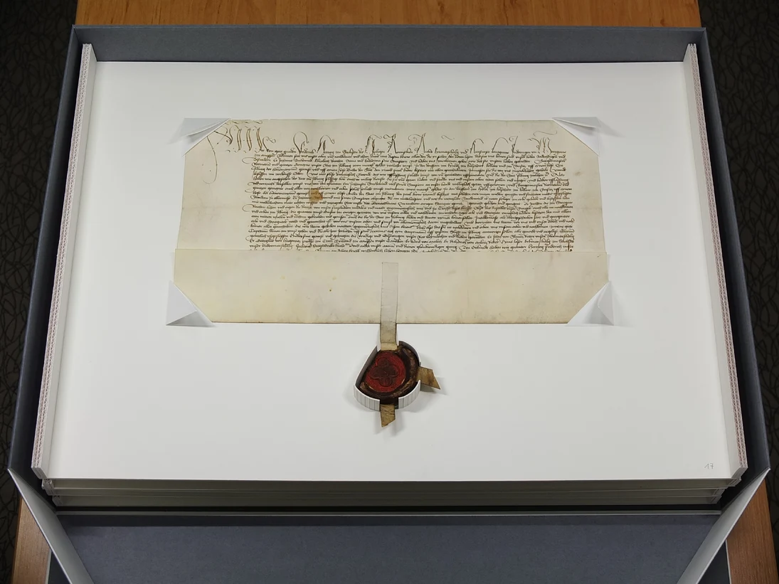 Geöffnete Klappschachtel mit Urkunde und anhängendem Siegel.