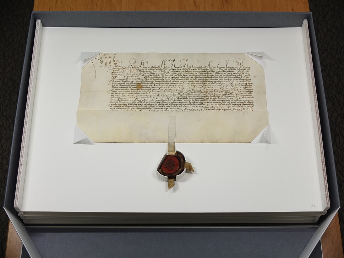 Geöffnete Klappschachtel mit Urkunde und anhängendem Siegel.