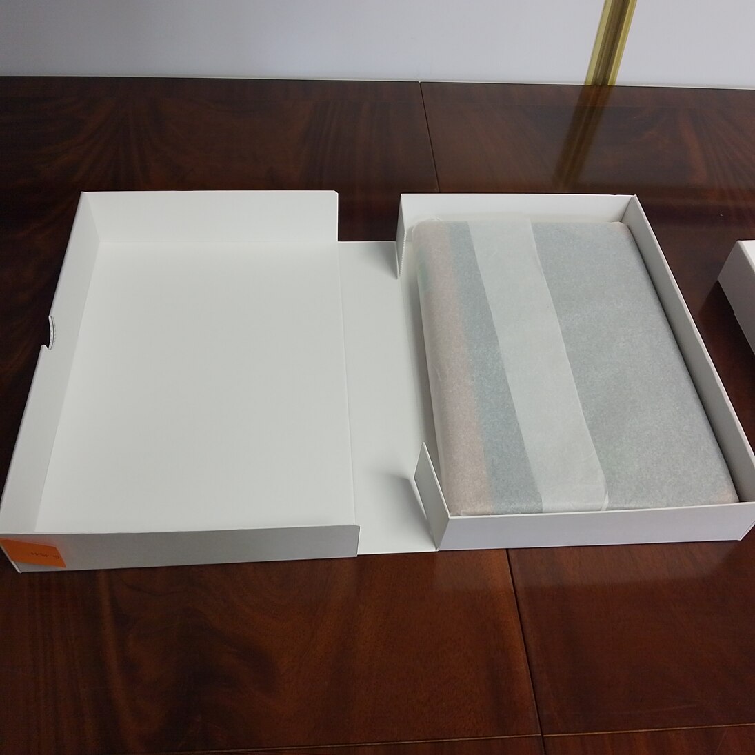 Geöffnete Schachtel mit in Seidenpapier eingeschlagenem Personenstandsbuch.